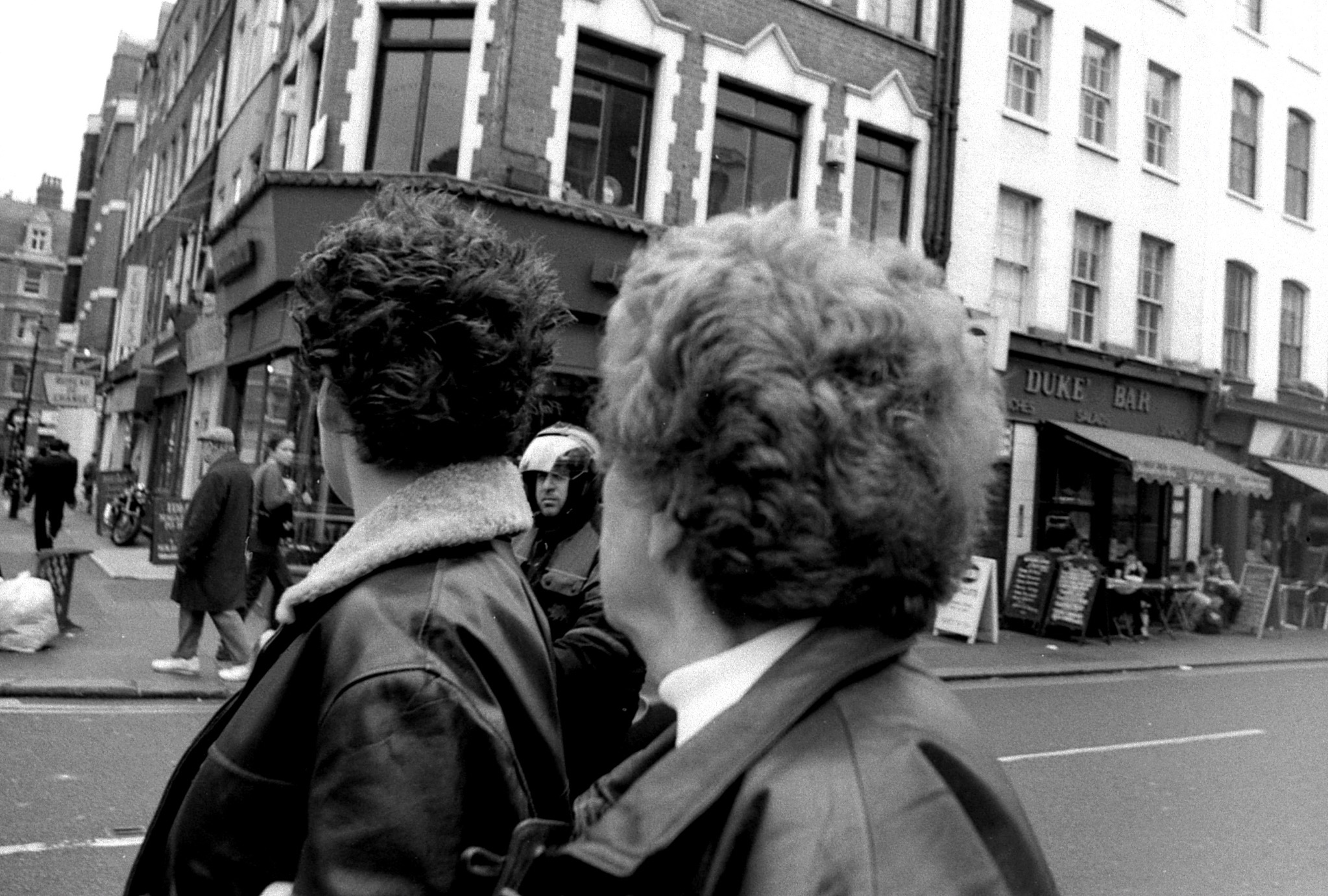 Street photograph, two figures looking across a city road